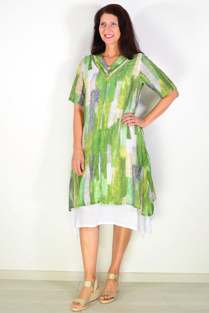 La Mode Shades of Green Summer Tunic Dress hanging on a hanger with leafy background, lightweight fabric and vibrant green tones.