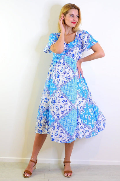 Soft blue floral paisley tunic dress by Hourglass, featuring a flowing fabric and intricate pattern, displayed on a hanger.