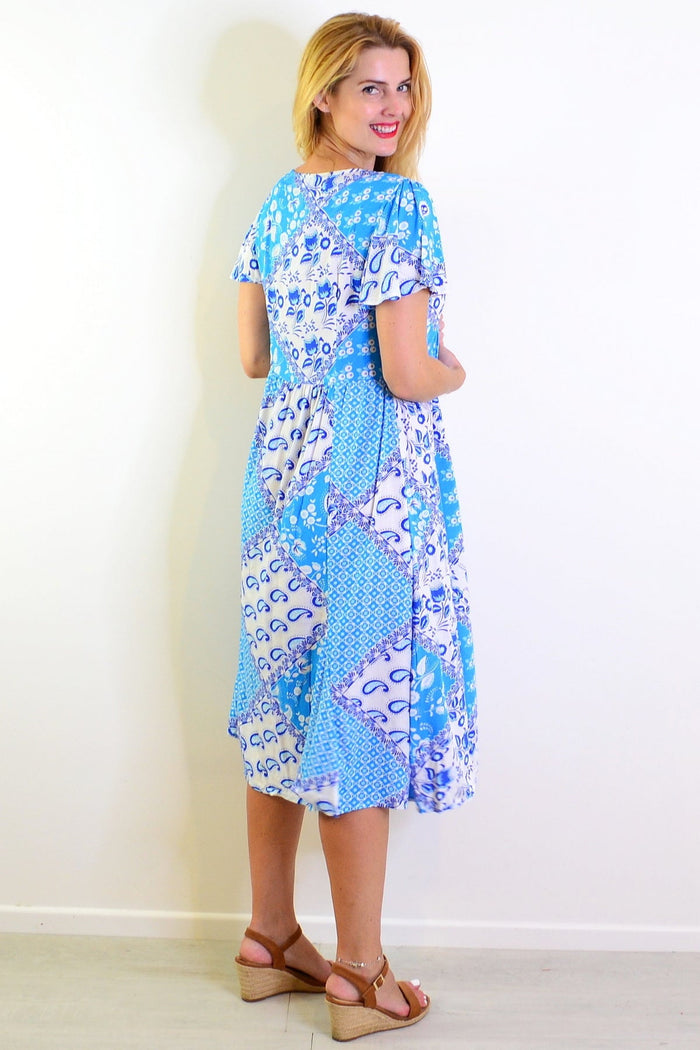 Soft blue floral paisley tunic dress by Hourglass, displayed on a hanger showing its flowy fabric and detailed floral pattern.