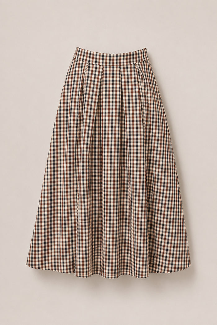 The Sophia Skirt in Chestnut Gingham by Ivy City Co is a mid-length, high-waisted skirt with a flared silhouette, featuring a checkered gingham pattern in shades of brown, beige, and black. Crafted from soft cotton fabric, this stylish skirt is showcased against a light background.