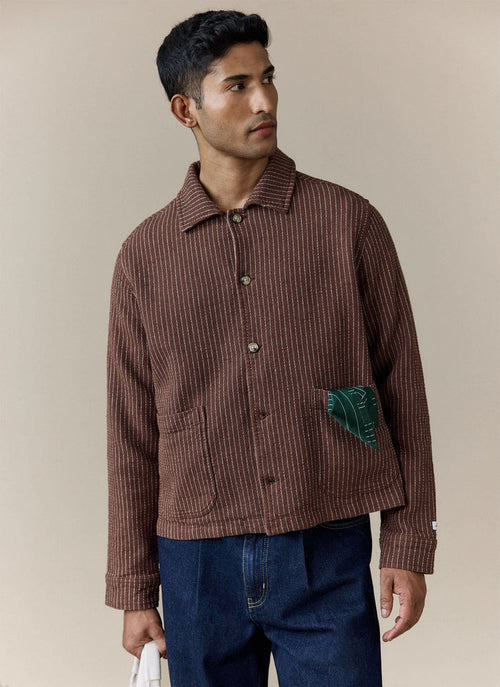 A model wears the Percival Sorrento Boxy Overshirt in brown, a textured linen-blend jacket with vertical white stitching.