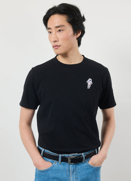 A model wears the Percival Spaceman T-Shirt in black organic cotton with blue jeans against a white studio background.