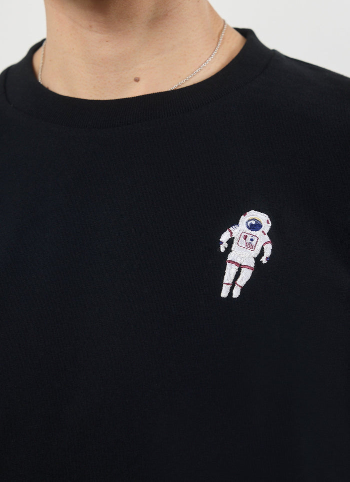 Close up of the spaceman embroidery on the black Percival t-shirt.