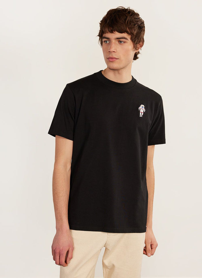 A model wears the black Percival Spaceman t-shirt, an organic cotton tee with a detailed spaceman embroidery on the chest.
