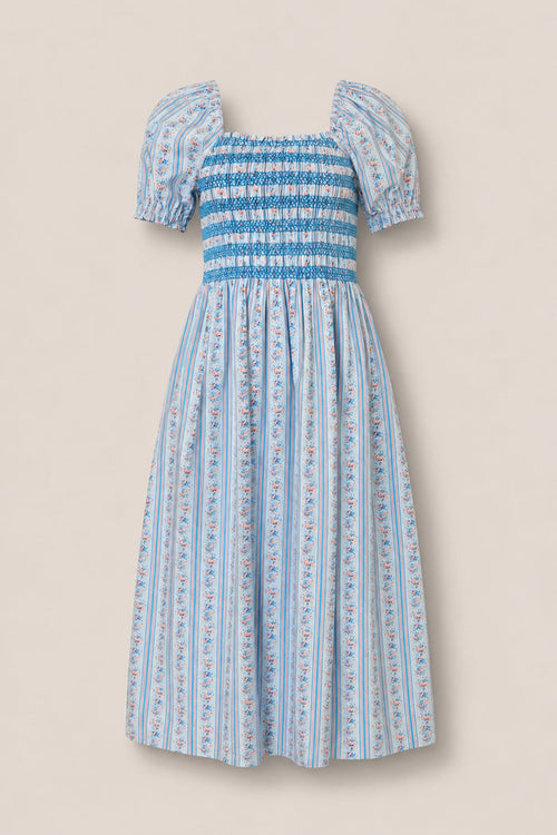 The Sunday Best Dress in Rosette Linear Stripe by Ivy City Co is a light blue, knee-length maternity dress with puffed sleeves, smocked bodice, flared skirt, vertical stripes, and pink-blue floral details for stylish comfort.
