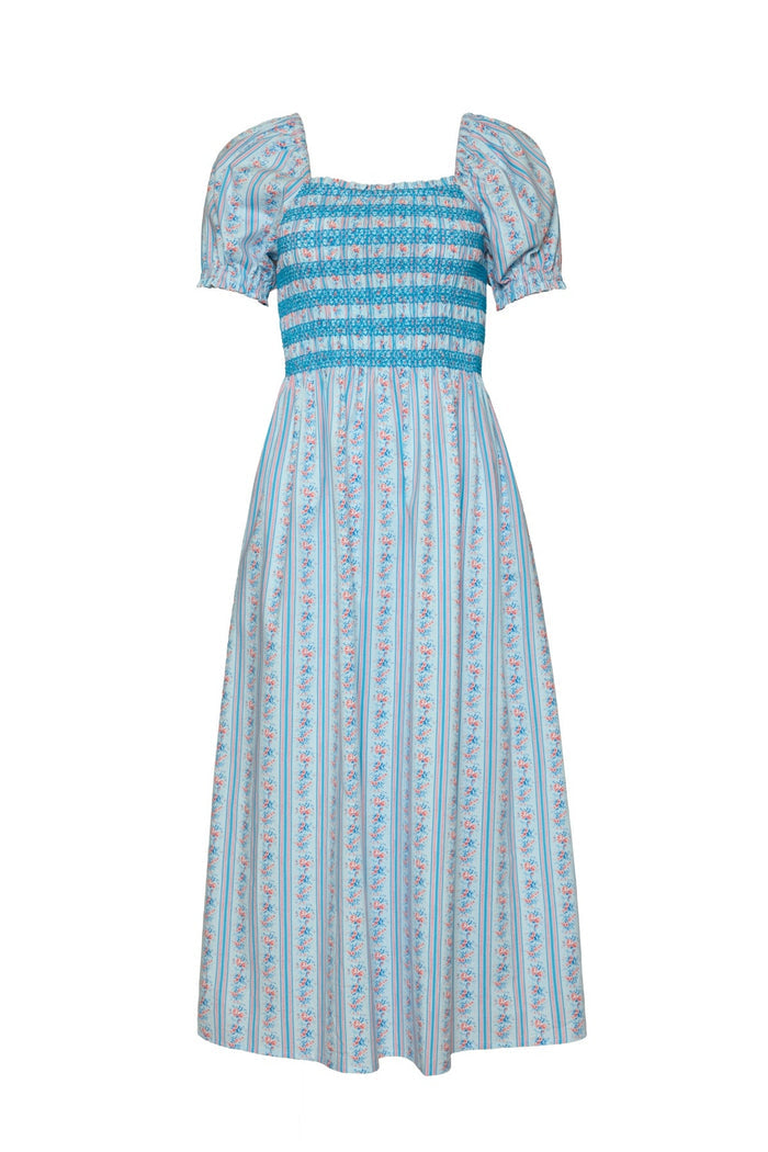 The Sunday Best Dress in Rosette Linear Stripe by Ivy City Co is a blue and white cotton midi dress featuring puffed short sleeves, a smocked bodice, and vertical floral stripe patterns. Designed with a square neckline and a loose, flowy fit from the waist down, this summer dress is beautifully maternity friendly as well.