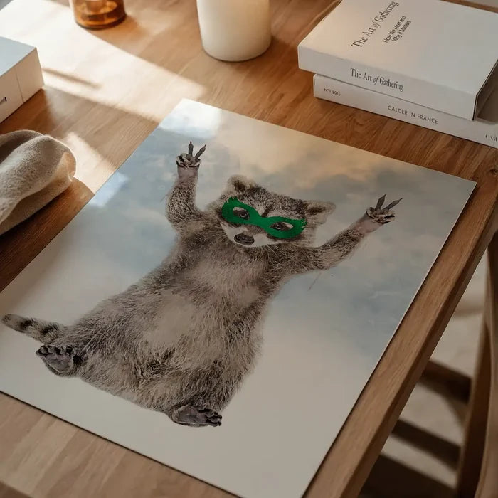 Watercolor art print of a raccoon wearing a green superhero mask, posing with peace signs against a cloudy sky background.