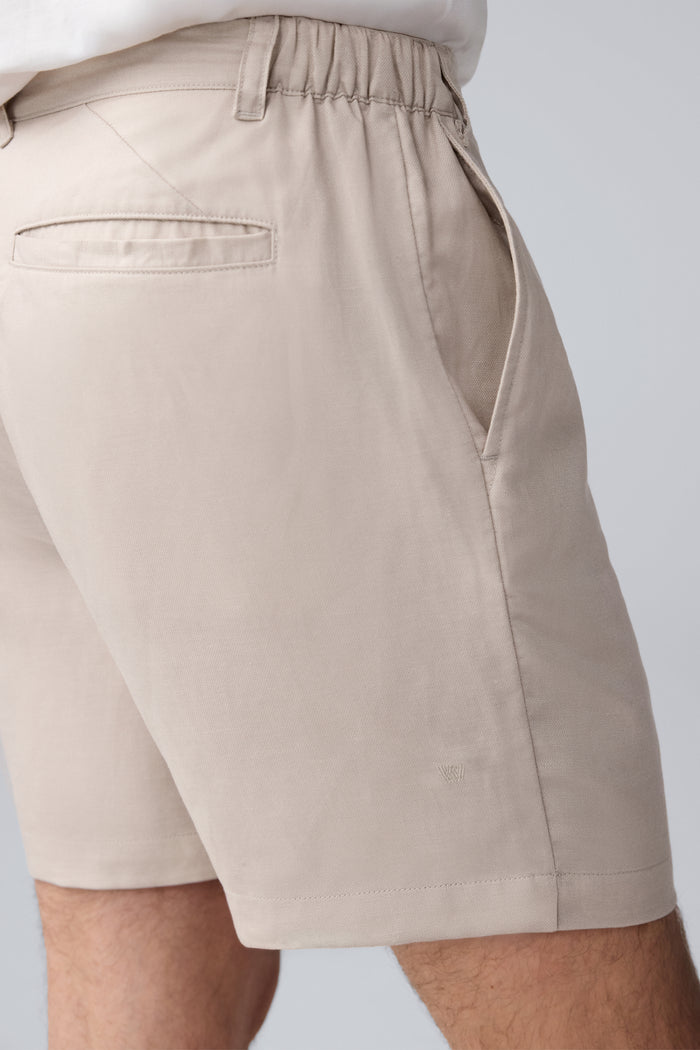 Detailed side view of a man wearing Tech Linen  Pleated Short in Natural Linen