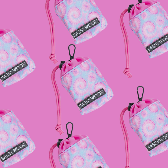 Sassy Woof Treat Pouch – Purple Haze, with a pastel tie-dye pattern, black clip, and pink cord, is displayed in a repeating pattern on bright pink—ideal to pair with matching harnesses from the Purple Haze collection.