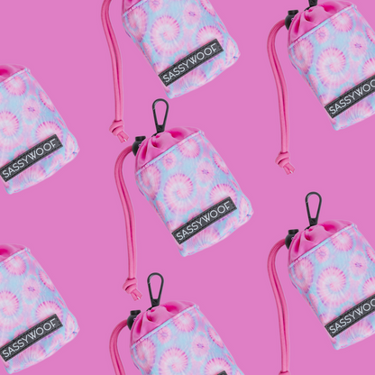 Sassy Woof Treat Pouch – Purple Haze, with a pastel tie-dye pattern, black clip, and pink cord, is displayed in a repeating pattern on bright pink—ideal to pair with matching harnesses from the Purple Haze collection.