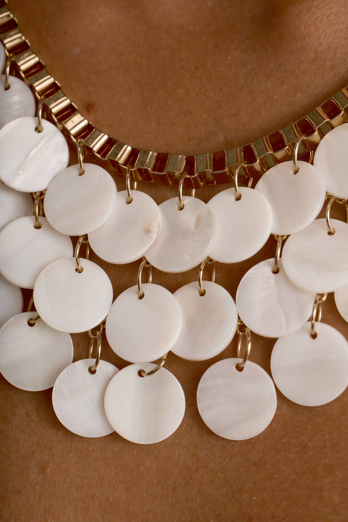 Close-up of the Ulla necklace, layered white shell discs on a gold chain.