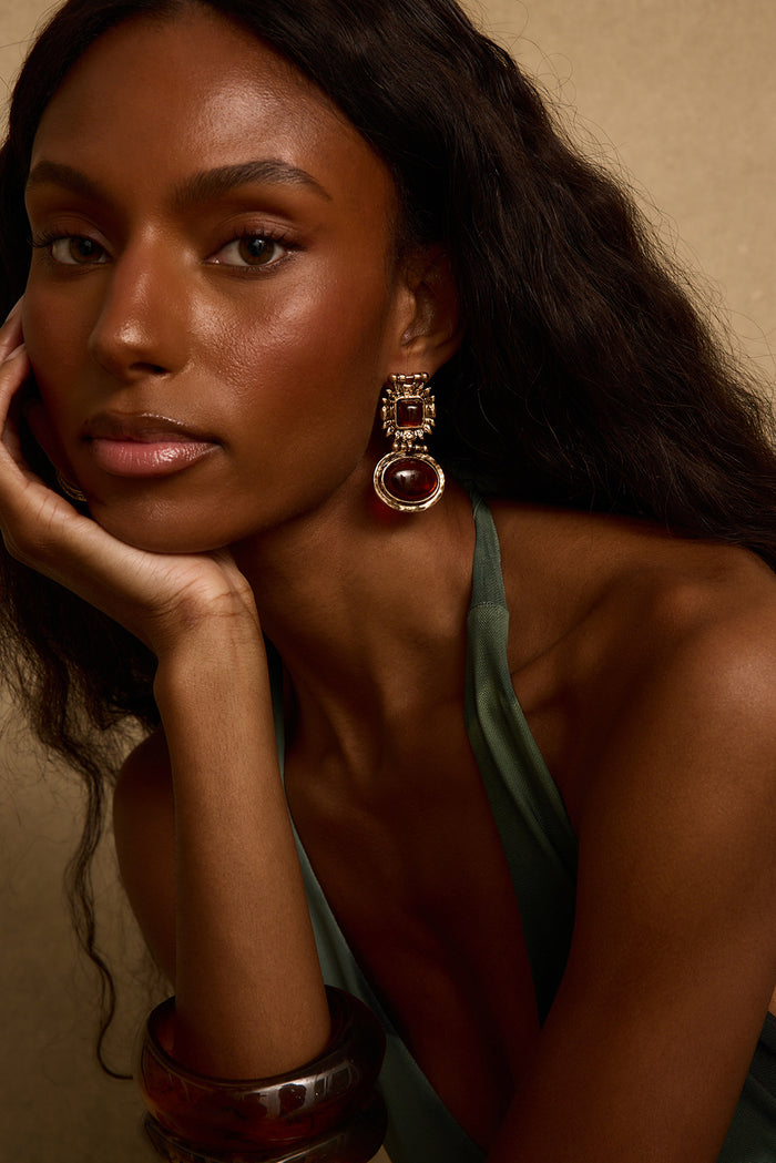 Villa Amber gold drop earring with chunky amber stone, worn with an olive halter top.