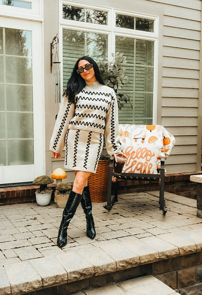 Women's tan turtleneck sweater with black wavy detail