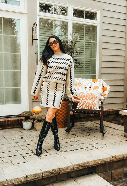 Women's tan turtleneck sweater with black wavy detail
