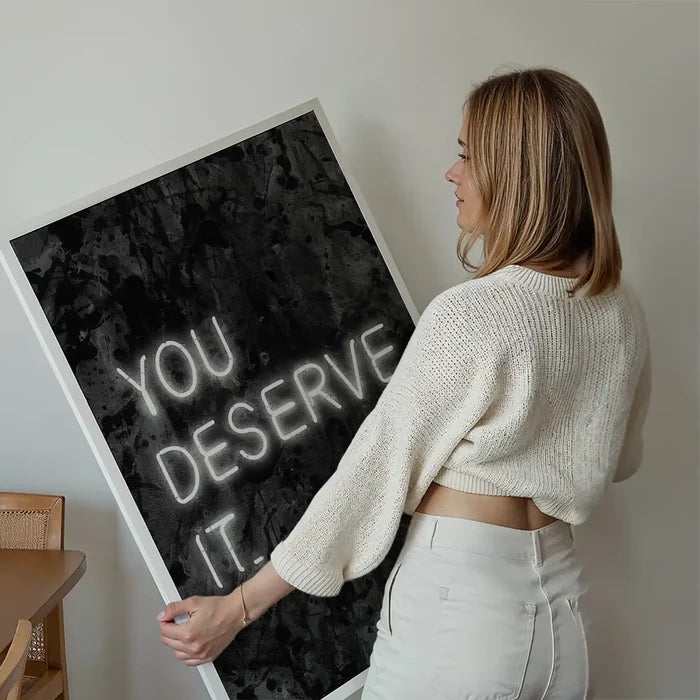 You Deserve It Neon Style Print held up against a living room wall