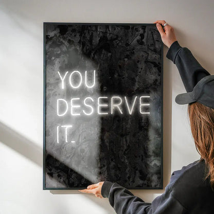 You Deserve It Neon Style Print being hung on a wall in a black frame